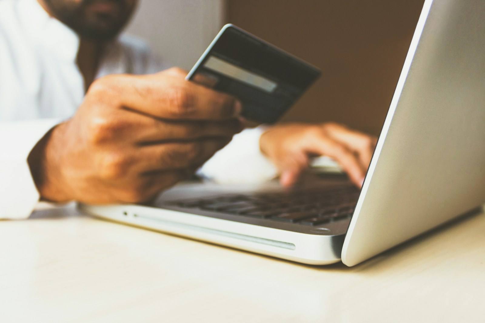 A person using a payment card and laptop for a secure online transaction